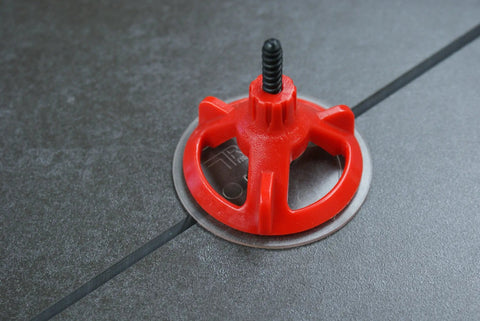 Red cap from Spin Doctor Tile Leveling System Caps 100 Piece Kit Reusable Caps Prevent Uneven Tiles With Large Format Floors on tile surface