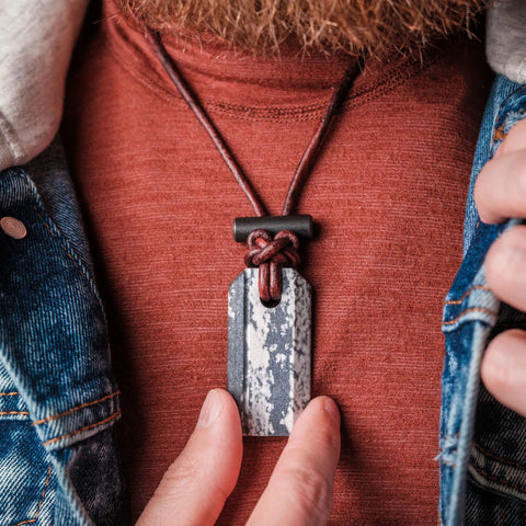 Viking Spark Whetstone Sharpener And Fire Starter Necklace worn on chest, featuring ferrocerium rod pendant and zirconia scraper.