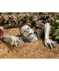 Zombie Of Montclaire Moors Indoor Outdoor Garden Statue Halloween Decor in mulch with flowers, 31 inches wide, resin material