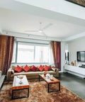 Living room with a ceiling fan and colorful decor, showcasing modern furniture and a spacious layout.