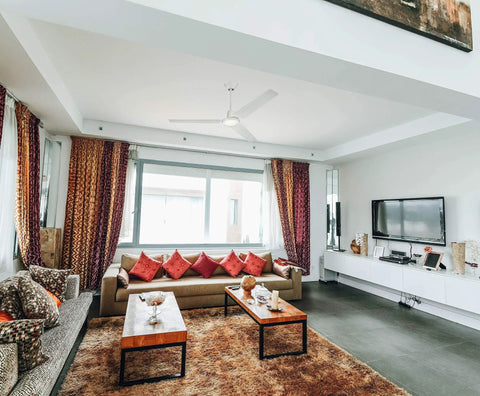 Living room with a ceiling fan and colorful decor, showcasing modern furniture and a spacious layout.