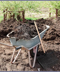 Wheelbarrow with manure next to Replacement 18 Tine Manure Fork Head 2 Pack With Screws And Nuts Beefy Pitchfork Rake in garden