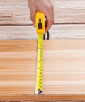 Hand measuring wooden board with yellow tape measure for 94 Piece Home And Auto Repair Tool Kit With Socket Wrench Set Pliers Screwdrivers And Mixed Hand Tools In Durable Toolbox Case For DIY Projects Home Maintenance And Auto Repairs