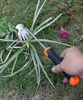 Hand using Weed Remover Tool With Rubber Handle Portable Garden Weeding Tool For Vegetable Gardens Backyards And Small Farms Hollow Hoe Design