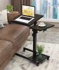 Mobile Adjustable Height Laptop Desk On Wheels Tiltable Work Table beside sofa, laptop on main surface, cup on mouse pad.