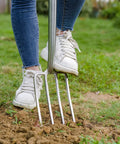Beefy 4 Tine Garden Digging Fork With Long Ash Wood Handle And D Grip For Digging Planting Cultivating And Aerating Stainless Steel Spading Tool For Backyard Gardeners used by a person on soil