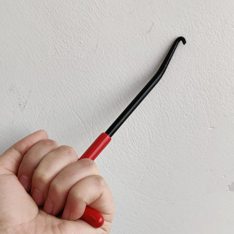 Side view of a red-handle rubber-coated motorcycle exhaust spring hook tool with a curved hooked end