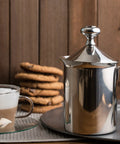 Handheld Milk Frother For Creamy Foam In Seconds, On The Go Stainless Steel Foamer next to glass cup with foam and cookies