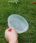 Person holding one of Two Pack Plastic Round Bird Feeder Bowls For Wild Birds Seed Tray And Water Bowl At Feeding Stations Easy To Clean Clear Water Visibility Attract Birds on grass