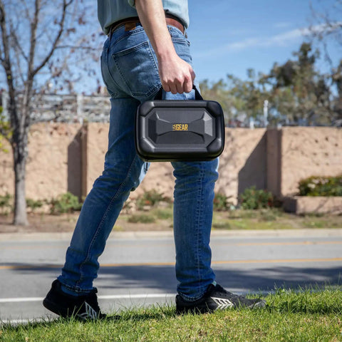 Heavy Duty Electronics Travel Crate With Custom Padded Dividers For Cables Chargers And Wireless Mouse Semi Rigid Hard Shell Case, carried by a person.
