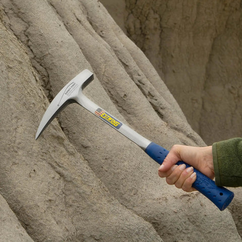 Rock Pick Hammer 22 Oz USA Made Geology Tool With Pointed Tip And Shock Reduction Grip held against a rock face