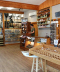 Fly fishing store interior with rods, reels, and gear displayed; wooden counters and racks in a spacious room.