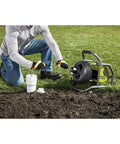 Powerful 18V Cordless Drain Auger Kit With 50 Ft Reel, 2Ah Battery, Charger, Pivoting Drum And Rubber Foot Pad in use outdoors.