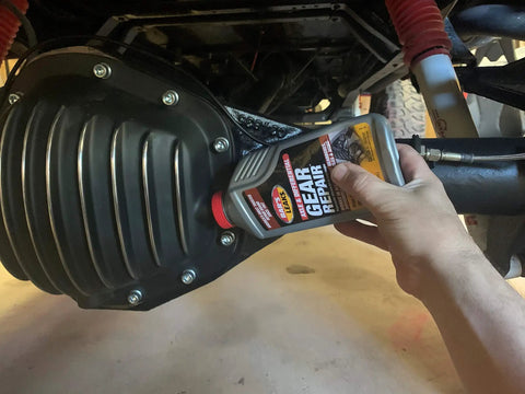 Top Tier Axle And Differential Gear Repair Fluid being poured into gear casing for automotive use.