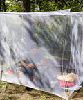 Rectangular Mosquito Net For Camping And Outdoors Lightweight Mesh Canopy installed over sleeping bag in forest setting