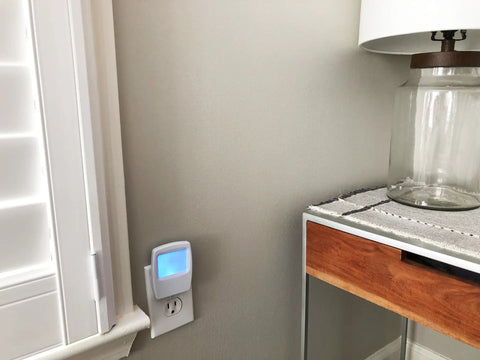 Always On Blue Night Light 4 Pack Plug In LED Slim Night Lights With A Soft Cool Glow installed in a room next to a table and lamp.