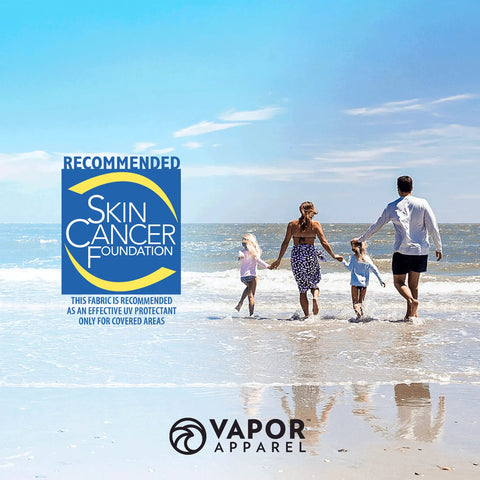 Family walking on beach with Skin Cancer Foundation logo, promoting Women's V Neck UPF 50 Plus Long Sleeve Sun Shield Tee in seagrass.