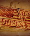 Wooden plank stamped with 'Made in the USA' over a faded American flag background design.