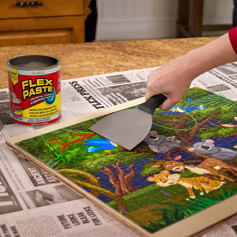 Person using a putty knife to apply Flex Paste on wooden surface with can in view, not related to waterproof paintable putty and spackle sealant.
