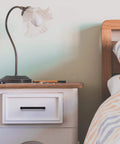 Bedroom nightstand with 60 Pack Sleek Matte Black Square Cabinet Handle and decorative lamp beside bed with striped bedding.