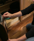 Person installing a trash bag holder inside a kitchen cabinet door, showing installation process and functionality.