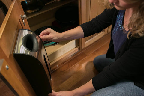 Person installing a trash bag holder inside a kitchen cabinet door, showing installation process and functionality.