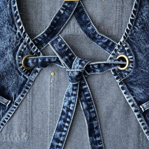 Close-up of Denim Apron For Men With Towel Loop And Tool Pockets, adjustable blue-black straps and brass rings, 100% cotton, special washed style.