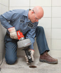 Professional Grade Pneumatic Air Powered 230V Drain Cleaning Tool used by technician to clear stubborn clogs in a bathroom.