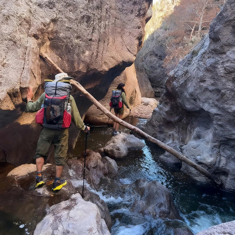 Hikers with backpacks crossing rocky stream, using Heavy Duty Nylon Pack Liner Bags 20 By 36 Inch 10 Pack Thick Five Point Five Mil Clear Liners.