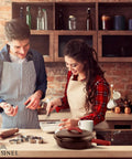 Couple cooking in kitchen with 12 Inch Cast Iron Skillet With Lid on stove, silicone handle visible on cookware.