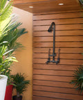 Outdoor Shower Kit With Soap Dish, Matte Black Finish, Corrosion And Rust Resistant, mounted on wooden panel in patio