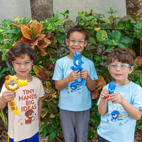 Kids wearing Kids Blue Safety Glasses Lightweight Protective Eyewear For School And Lab Use, holding colorful toys outdoors.