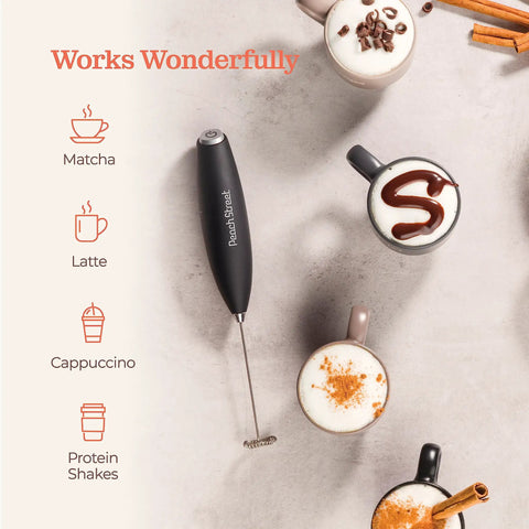 Game Changing Handheld Milk Frother Wand Battery Operated Stainless Steel Drink Mixer For Milk Coffee Lattes Cappuccino Frappe Matcha Hot Chocolate With Stand Gift on table with latte, cappuccino, and matcha drinks.