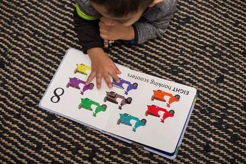 Child learning to count in the Totally Rad Toddler Counting Book Featuring Ten Noisy Rickshaws and Hella Fun Indian Culture.