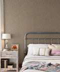 Taupe Metallic Grasscloth Peel And Stick Wallpaper Roll Featuring Faux Woven Texture With Subtle Shimmer in cozy bedroom setting.