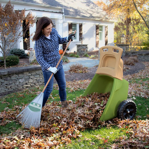 Woman raking leaves using Easy Haul Wheelbarrow Green Garden Cart For Yard Work With Wide Wheel And Durable Steel Frame
