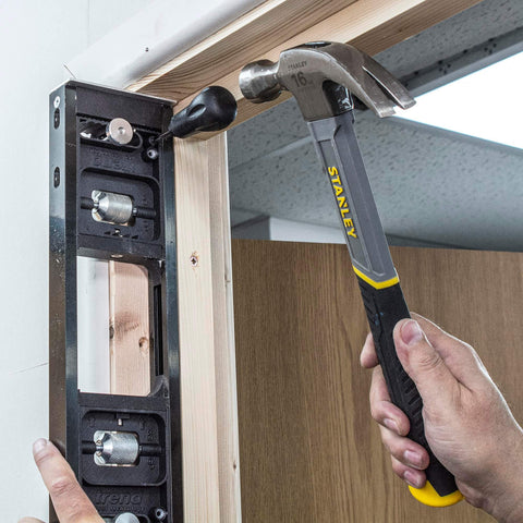 All-In-One Adjustable Door Hinge Jig Installation Kit For 2 Ft 6 In To 9 Ft Doors being used on a door frame with a hammer by Trend