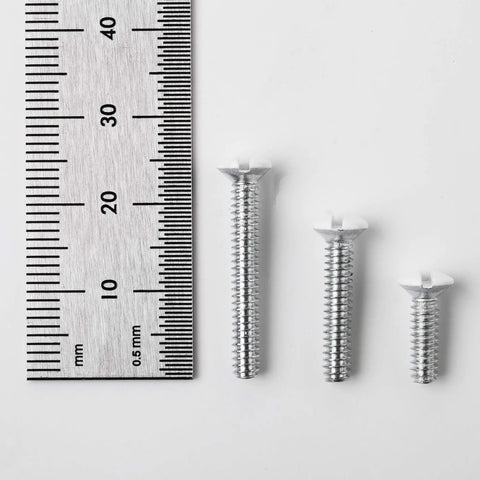 Three assorted size screws from 75 Pack Wall Plate Screws Set With Slotted Oval Heads For Outlets And Light Switches, next to a ruler.