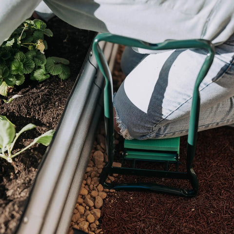Person using the 2-In-1 Garden Kneeler And Seat With Cushioned Pad, Foldable Stool for weeding next to garden bed