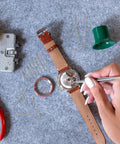 Person working on a watch with tools, using Must-Have 360 Piece Stainless Steel Watch Band Pins Kit With 18 Sizes From 6mm To 23mm for repairs.