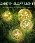 Solar Globe Lights 6 Inch Outdoor Crackled Glass Orbs glowing warm yellow in grass for patio yard backyard decor, set of four