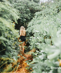 Person walking through lush green foliage path, nature setting, lush greenery surrounding.