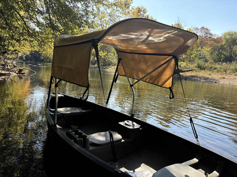 Beige Canoe And Kayak Sun Shade Canopy Bimini Top In Conestoga Wagon Style With Two Removable Zippered Side Curtains on water