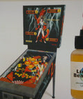 100 Percent Synthetic HO Slot Car Oil That Displaces Old Oils And Boosts Speed, with needles, shown next to pinball machine