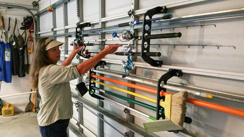 Person organizing rods on Garage Door Storage Rack for Fishing Gear 21 Inch Black ABS Rod Holder Lets You Hook Up Saltwater Tackle Fast