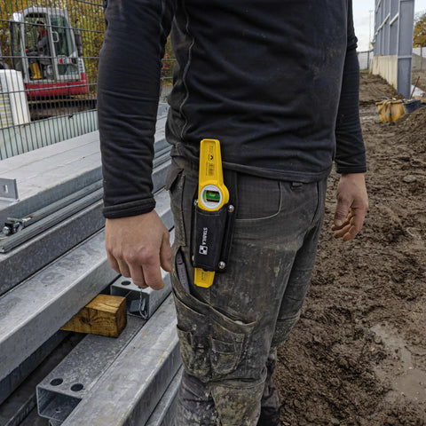 Worker wearing Magnetic Level With Holster 81S10MH For Steel Erectors And Scaffolders attached to belt on construction site.