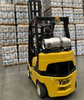Aluminum 33.5 lb forklift propane tank with gauge mounted on back of yellow Yale forklift in warehouse.