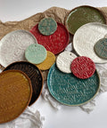 Assorted embossed clay pottery with intricate patterns in various colors on a textured surface.
