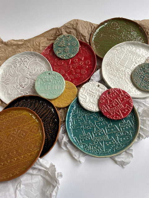Assorted embossed clay pottery with intricate patterns in various colors on a textured surface.