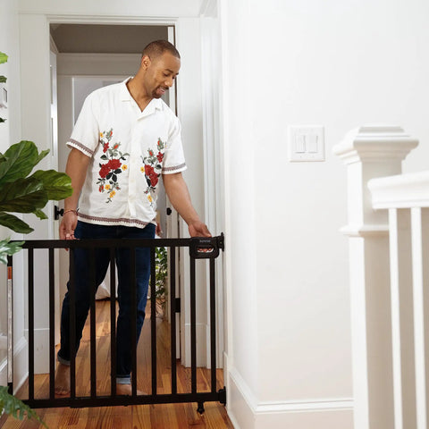 Man securing Deluxe Stair Gate For Pets And Kids, Super Easy Install No Fuss Secure Build, Black Wood, in hallway